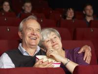 Et lykkeligt par er i biogafen. Den smiler og spiser popcorn. Det er en rigtig god fiml.