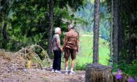 Ældre par står hånd i hånd ude i naturen 